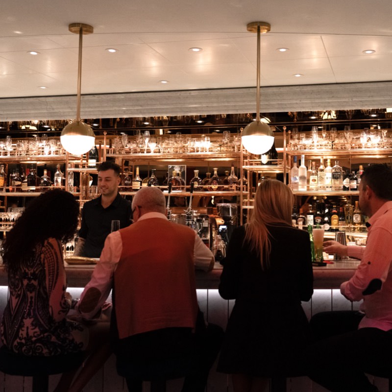 Craft cocktail being served at a bar using bar tab on Virgin Voyages